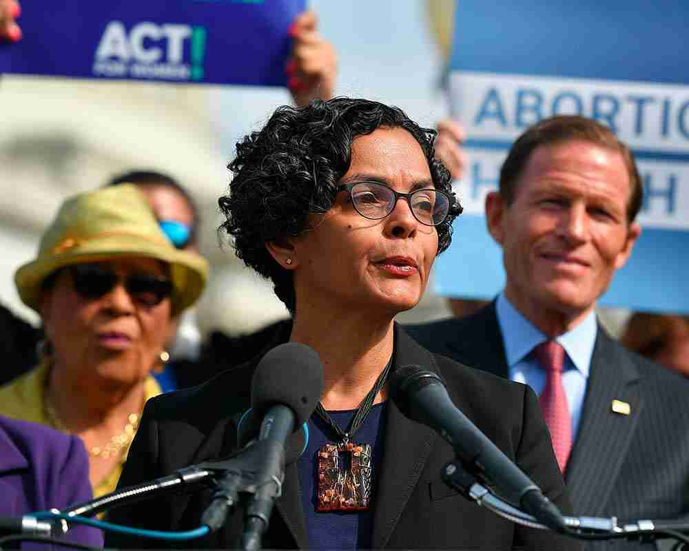 Lourdes Rivera, senior vice president of the Center for Reproductive Rights, speaks during a press conference surrounded by people holding sign.